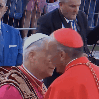 A Man In A Red Hat Talks To Another Man GIF