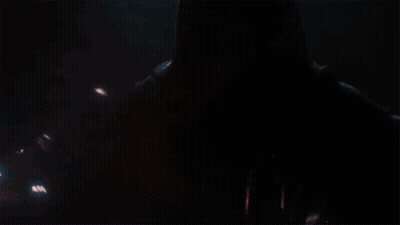 A Man In A Red Helmet Is Holding A Red Light Saber In The Dark . GIF