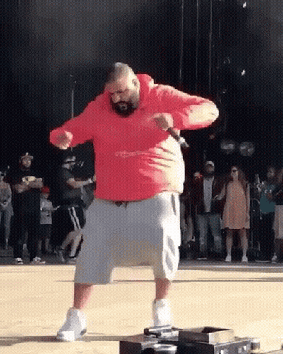 A Man In A Red Hoodie And Shorts Is Dancing On A Stage . GIF