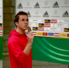 A Man In A Red Hoodie Is Eating An Ice Cream Cone In Front Of An Adidas Wall GIF