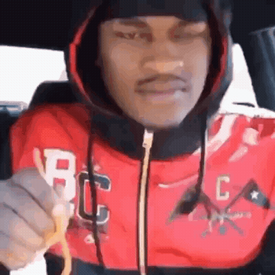 A Man In A Red Hoodie Is Holding A French Fry In His Hand . GIF