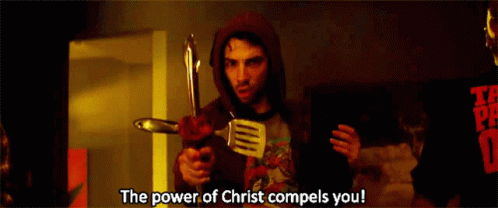 A Man In A Red Hoodie Is Holding A Spatula And A Knife And Says The Power Of Christ Compels You GIF