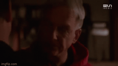 A Man In A Red Hoodie Is Looking At Another Man . GIF