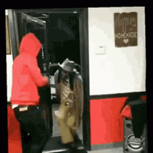 A Man In A Red Hoodie Is Standing In A Doorway Next To A Sign That Says " Happiness Homemade " GIF