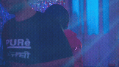 A Man In A Red Hoodie Is Standing In Front Of A Neon Ring GIF