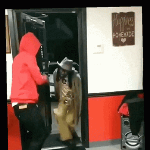 A Man In A Red Hoodie Is Standing In Front Of A Sign That Says Happiness And Homemade GIF