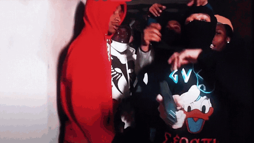 A Man In A Red Hoodie Is Standing Next To A Man In A Black Shirt With Donald Duck On It GIF