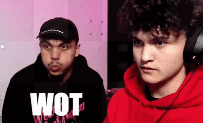 A Man In A Red Hoodie Is Standing Next To Another Man In A Black Hat . GIF