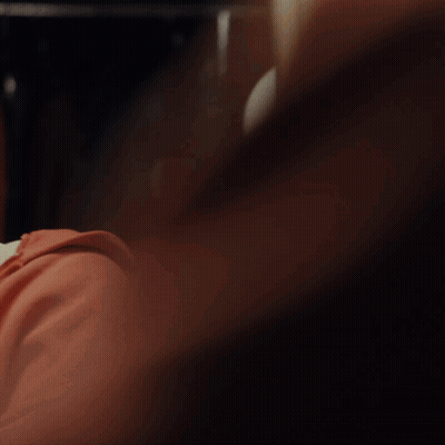 A Man In A Red Hoodie Looks At Himself In The Mirror GIF