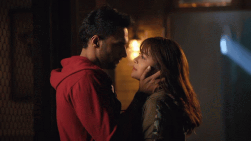 A Man In A Red Hoodie Touches A Woman 'S Forehead GIF