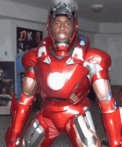 A Man In A Red Iron Man Suit Is Standing In Front Of A Dk Sign GIF