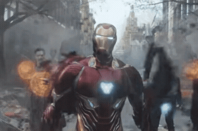 A Man In A Red Iron Man Suit Is Walking Down A City Street GIF