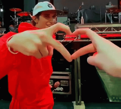 A Man In A Red Jacket And Hat Is Making A Heart With His Hands . GIF