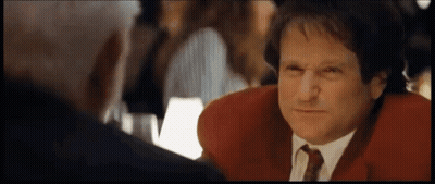 A Man In A Red Jacket And Tie Is Talking To Another Man In A Restaurant . GIF