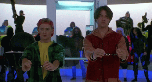 A Man In A Red Jacket Holds A Pair Of Glasses Next To Another Man In A Yellow Shirt GIF