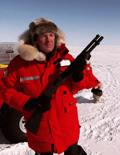 A Man In A Red Jacket Holds A Shotgun In The Snow GIF