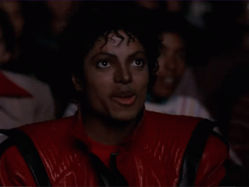 A Man In A Red Jacket Is Clapping His Hands In A Crowd GIF