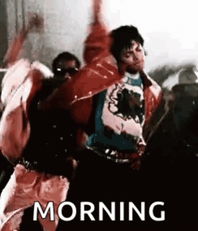 A Man In A Red Jacket Is Dancing In Front Of A Crowd With His Hands In The Air . GIF
