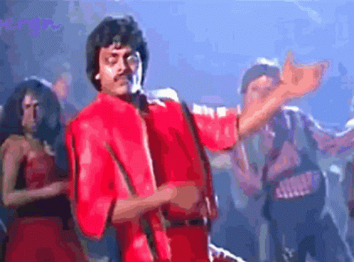 A Man In A Red Jacket Is Dancing In Front Of A Group Of People GIF