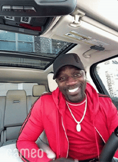 A Man In A Red Jacket Is Driving A Car GIF