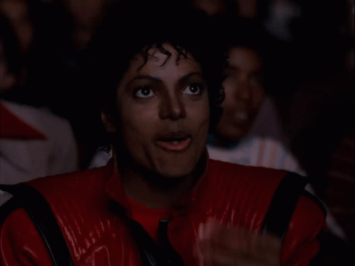 A Man In A Red Jacket Is Eating A Piece Of Popcorn GIF