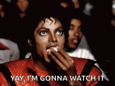A Man In A Red Jacket Is Eating Popcorn And Saying `` Yay , I 'M Gonna Watch It '' GIF