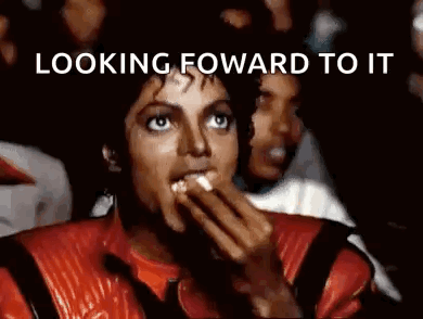 A Man In A Red Jacket Is Eating Popcorn In Front Of A Crowd . GIF