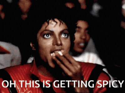 A Man In A Red Jacket Is Eating Popcorn With The Words Oh This Is Getting Spicy Below Him GIF