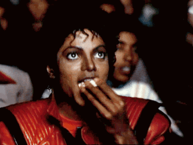 A Man In A Red Jacket Is Eating Something With His Mouth Open GIF