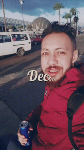 A Man In A Red Jacket Is Holding A Can Of Soda And The Word Decos Is On The Bottom GIF