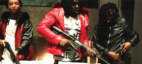A Man In A Red Jacket Is Holding A Gun In Front Of Two Other Men GIF