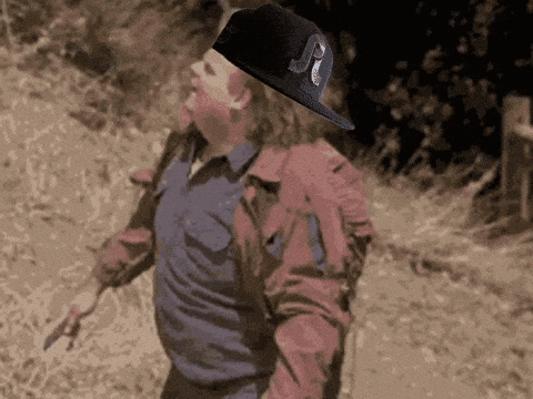 A Man In A Red Jacket Is Holding A Knife And A Hat With The Letter P On It GIF