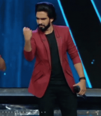 A Man In A Red Jacket Is Holding A Microphone And His Fist In The Air GIF