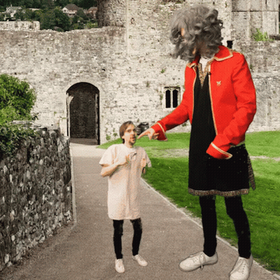 A Man In A Red Jacket Is Pointing At A Little Girl GIF