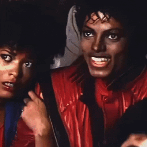 A Man In A Red Jacket Is Smiling Next To A Woman In A Blue Shirt GIF