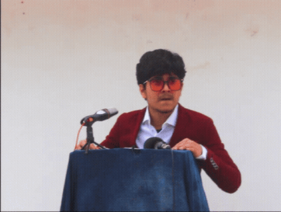 A Man In A Red Jacket Is Standing At A Podium With A Microphone GIF