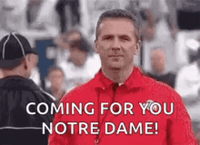 A Man In A Red Jacket Is Standing In Front Of A Crowd Of People . GIF