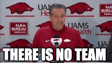 A Man In A Red Jacket Is Standing In Front Of A Microphone With The Words `` There Is No Team '' . GIF