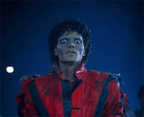 A Man In A Red Jacket Is Standing In Front Of Zombies GIF