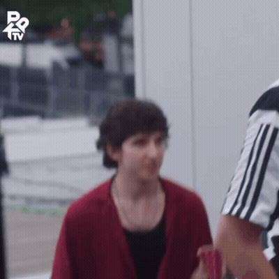 A Man In A Red Jacket Is Standing Next To A Referee In A Black And White Shirt GIF