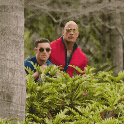 A Man In A Red Jacket Is Standing Next To Another Man In A Blue Shirt . GIF