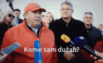 A Man In A Red Jacket Is Talking Into A Microphone With The Words Kome Sam Duzan GIF