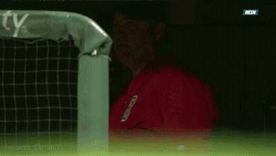 A Man In A Red Jacket Is Talking On A Cell Phone In A Dugout GIF