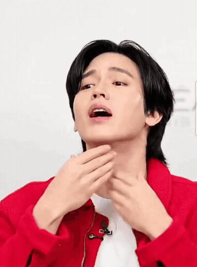 A Man In A Red Jacket Is Touching His Face GIF