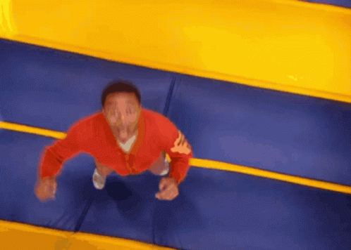 A Man In A Red Jacket Jumps On A Trampoline GIF
