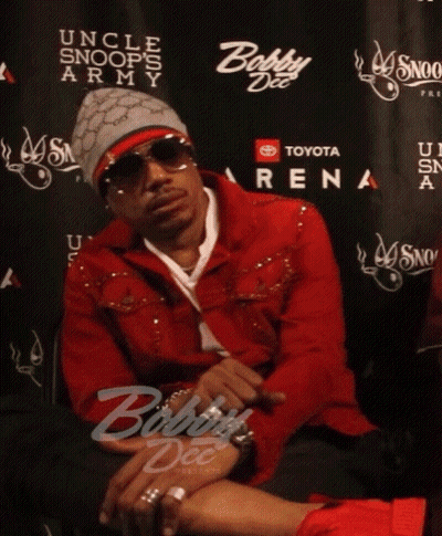A Man In A Red Jacket Sits In Front Of A Wall That Says Toyota Arena GIF