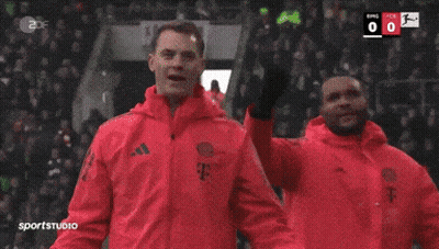 A Man In A Red Jacket Stands In Front Of A Scoreboard That Says Sportstudio GIF