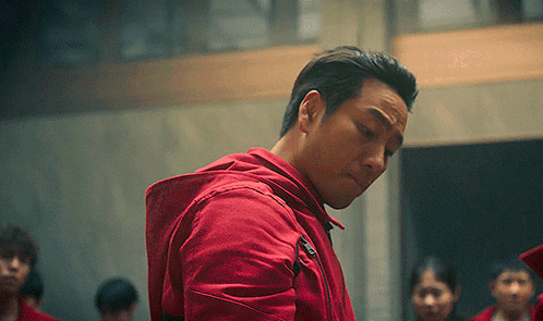A Man In A Red Jacket With A Hood Is Standing In Front Of A Group Of People GIF