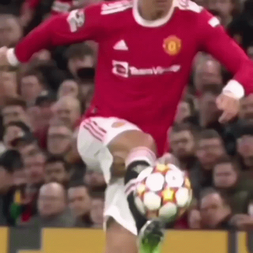A Man In A Red Jersey Is Kicking A Soccer Ball . GIF