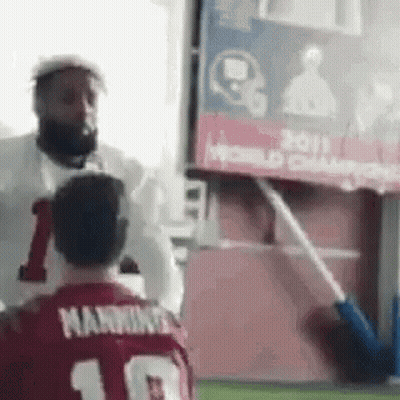 A Man In A Red Jersey With The Number 10 On It Is Standing Next To Another Man In A White Shirt . GIF